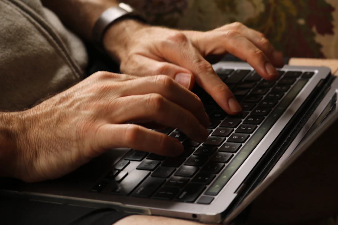Des mains travaillent sur le clavier d’un ordinateur portable.